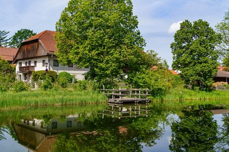 Häuser am Teich mit Holzsteg in Bayern